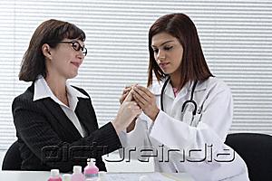 PictureIndia - Doctor applying bandage to patient's finger