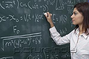 PictureIndia - Woman working on equations on chalk board