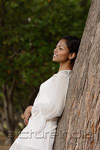 PictureIndia - woman leaning on tree, looking away