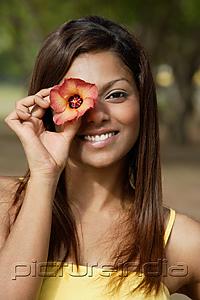 PictureIndia - woman covering an eye with flower, smiling
