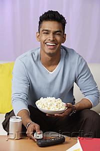 PictureIndia - young man holding popcorn in hand, laughing
