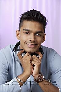 PictureIndia - young man with headphones around his neck, smiling at camera