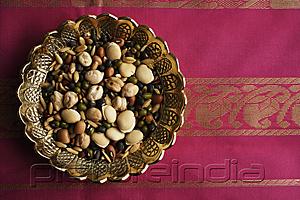 PictureIndia - Mix of Indian beans, seeds and nuts in brass dish on pink sari cloth