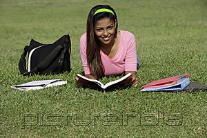 PictureIndia - young woman laying on grass studying