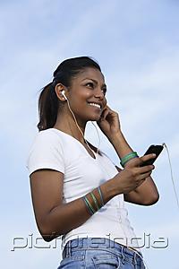 PictureIndia - Young woman listening to a MP3 player.
