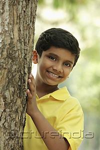 PictureIndia - Young boy peeking out from behind a tree