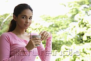 PictureIndia - Young woman holding cup looking at camera
