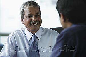 PictureIndia - Two businessmen smiling at each other