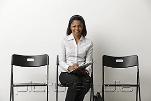 PictureIndia - Young Indian woman fills out form and waits in waiting room