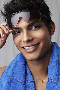 PictureIndia - head shot of young man holding sunglasses and wearing a towel around his neck