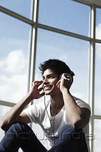 PictureIndia - young man wearing head phones while looking out the window