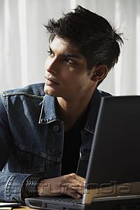 PictureIndia - young man at laptop looking away