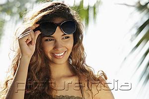 PictureIndia - young woman smiling and holding up her sunglasses