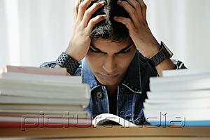 PictureIndia - young man holding his head while reading