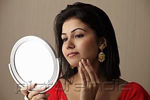 PictureIndia - head shot of woman looking at her face in the mirror