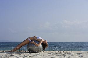 Mind Body Soul - woman in bikini lying on giant ball on beach