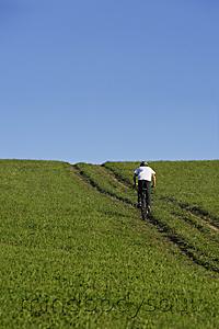Mind Body Soul - Young man riding bicycle up meadow path