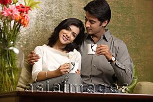 Asia Images Group - couple hold up tea cups, man looks at woman
