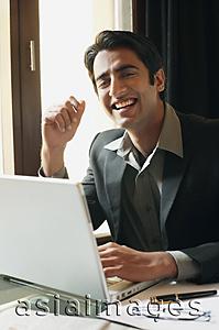 Asia Images Group - business man working at laptop, laughing