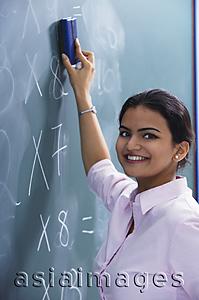 Asia Images Group - teacher smiling as she erases at chalkboard
