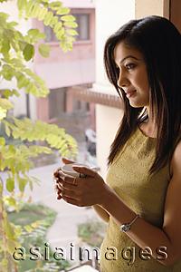 Asia Images Group - lady by window holding tea cup