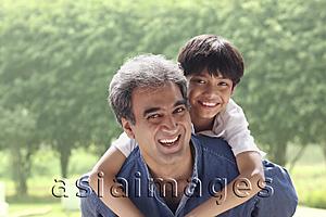 Asia Images Group - Father with son on his back, both smiling at camera