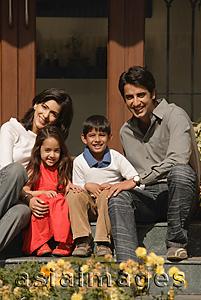 Asia Images Group - family of four sitting front doorstep, smiling at camera