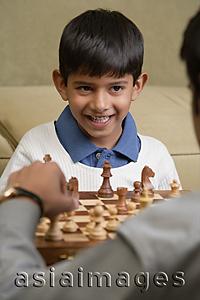 Asia Images Group - boy plays chess with father and smiles (vertical)