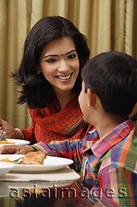 Asia Images Group - mother smiles to son at dinner table