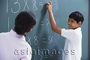 Asia Images Group - back of teacher, boy at chalkboard