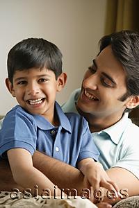 Asia Images Group - father hugging son on couch, son smiles at camera