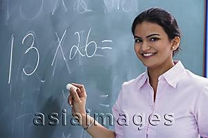 Asia Images Group - teacher smiling as she writes at chalkboard
