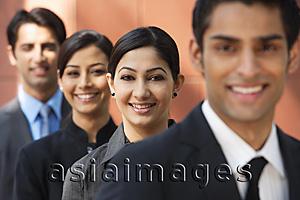 Asia Images Group - businessman in foreground, three colleagues in background, all smiling and looking at camera