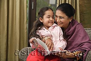 Asia Images Group - granddaughter sits on grandmother's lap for story (horizontal)