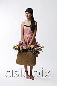 AsiaPix - Young woman holding straw bag full of flowers