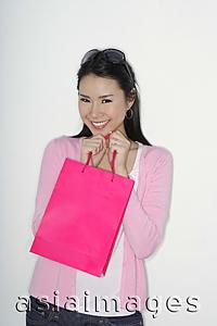 Asia Images Group - woman holding shopping bag to chin