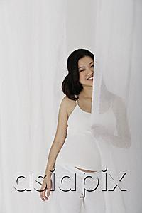 AsiaPix - Pregnant woman standing behind curtain
