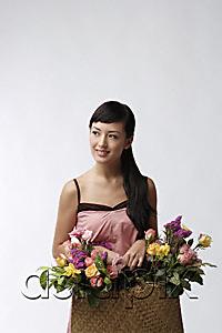 AsiaPix - Young woman holding straw bag full of flowers