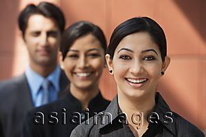 Asia Images Group - two businesswomen smiling at camera, one businessman (first woman in focus)