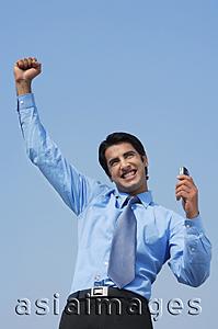 Asia Images Group - smiling business man with fist in air, phone in hand