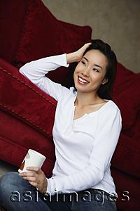 Asia Images Group - woman sitting on floor holding coffee cup