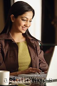 Asia Images Group - smiling woman working at laptop with coffee