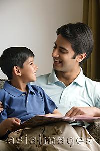 Asia Images Group - father and son smiling at each other, story book