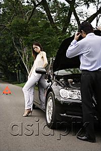 AsiaPix - Man looking under hood of car while woman waits