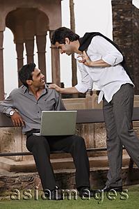 Asia Images Group - men talking outside, one working at laptop computer