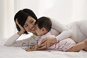 AsiaPix - Woman lying on bed with baby girl