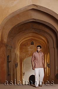 Asia Images Group - man walking up arched hallway