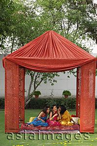 Asia Images Group - three young women in saris, chatting in tent