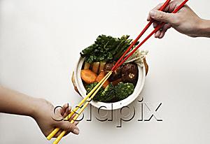AsiaPix - hands holding chopsticks in clay pot of vegetables