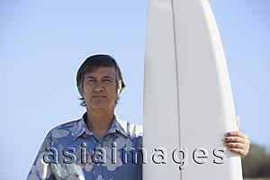 Asia Images Group - mature man standing next to surf board